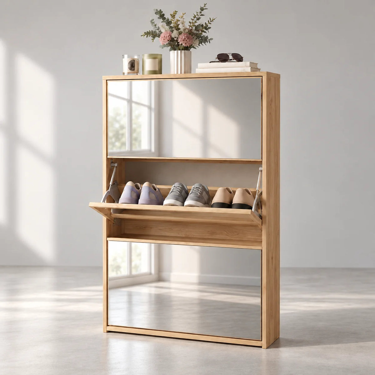 Meuble à chaussures en bois clair avec deux façades miroir et compartiment central ouvert sur fond gris