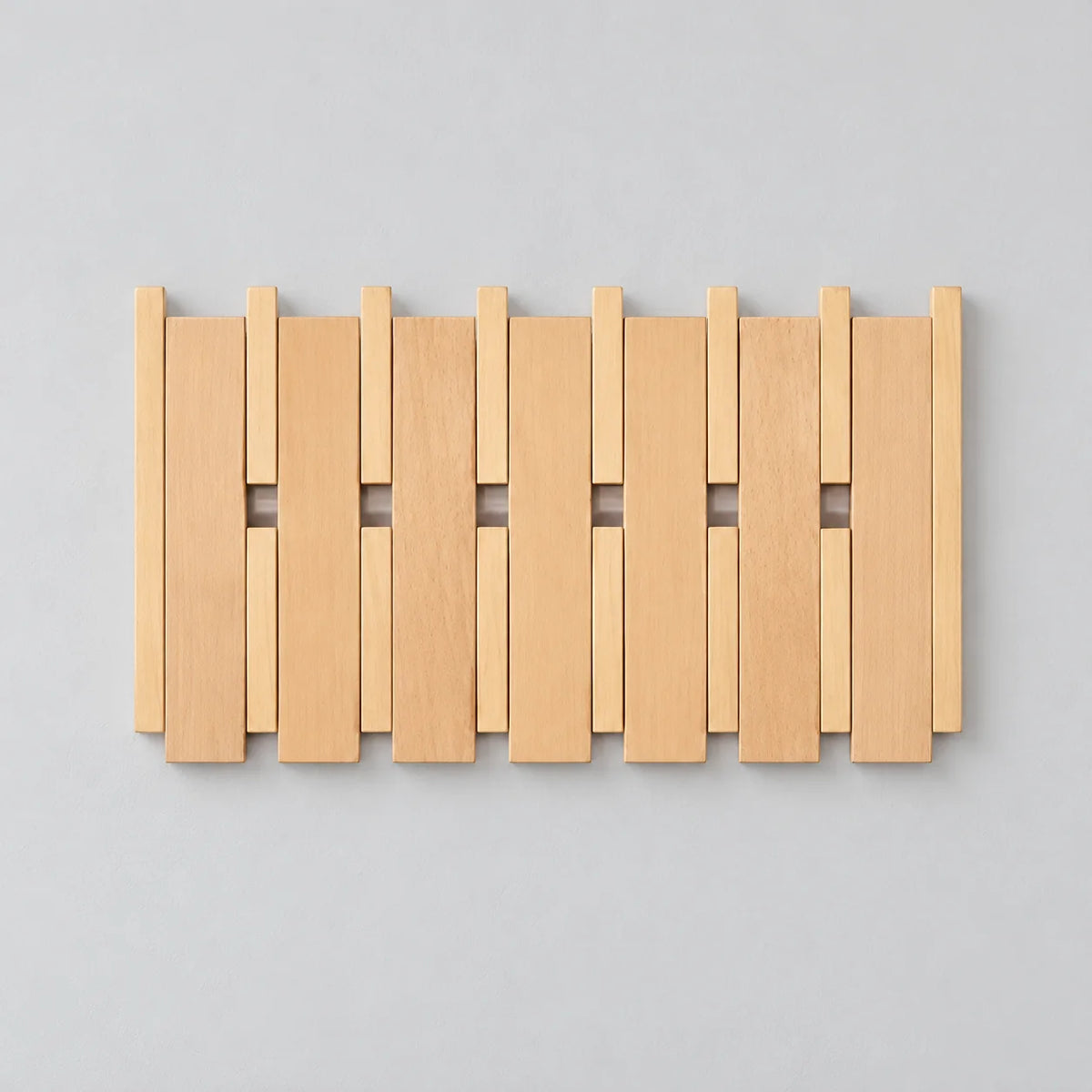 Porte-manteau mural carré large en bois clair, lattes et crochets rabattables fermés sur fond gris