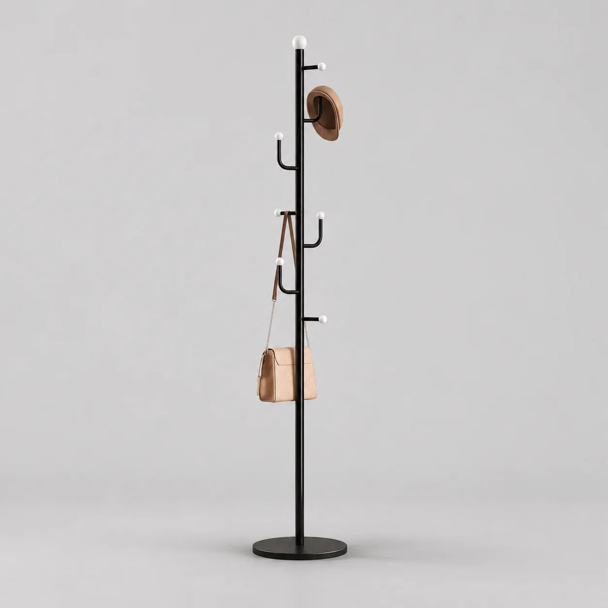 Porte-manteau noir sur pied à embouts blancs et base ronde avec chapeau et sac sur fond gris Image