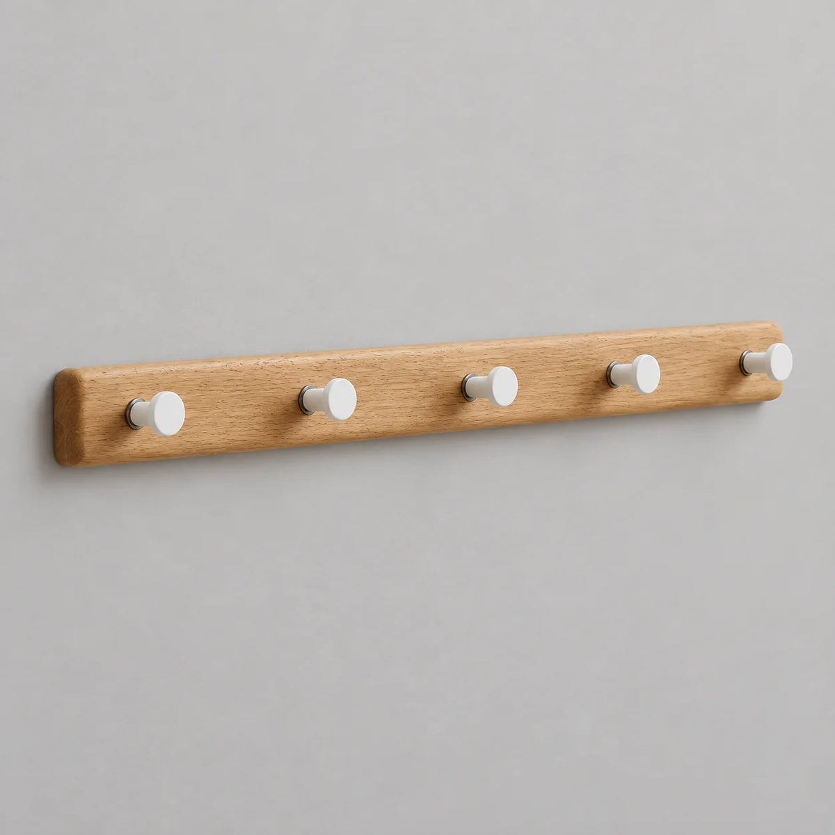 Porte-manteau mural en bois clair à cinq crochets blancs sur fond gris