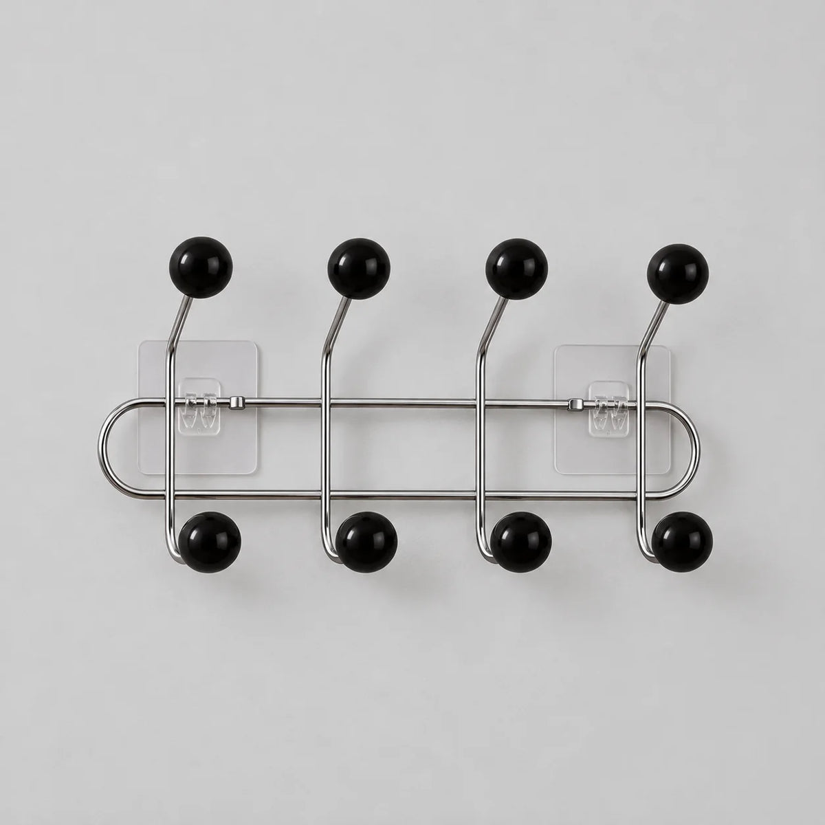 Porte-manteau mural chromé à quatre bras et huit boules noires sur fond gris