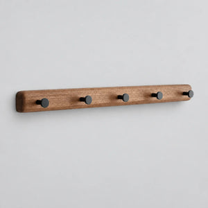 Porte-manteau mural en bois brun avec cinq crochets noirs, sur fond gris