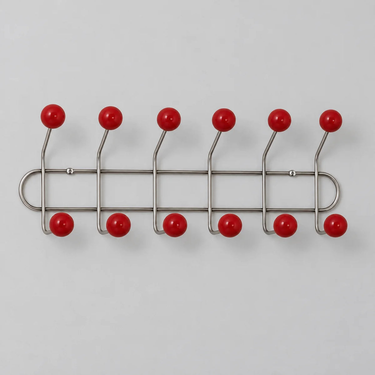 Porte-manteau mural en métal chromé avec douze embouts rouges, sur fond gris