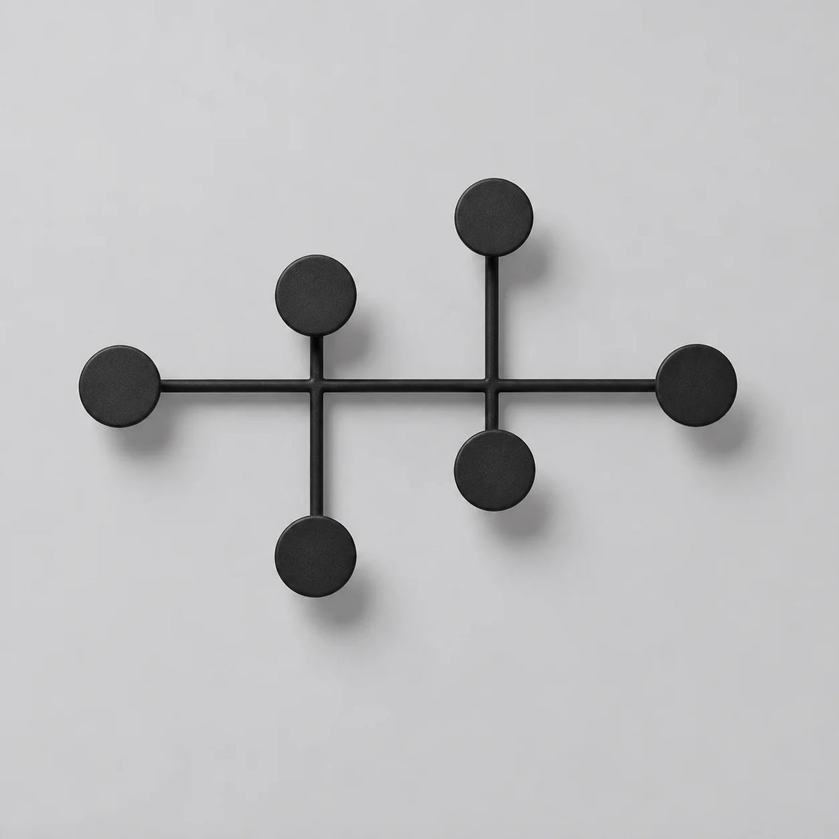 Porte-manteau mural rond noir à six patères circulaires, vue de face sur fond gris