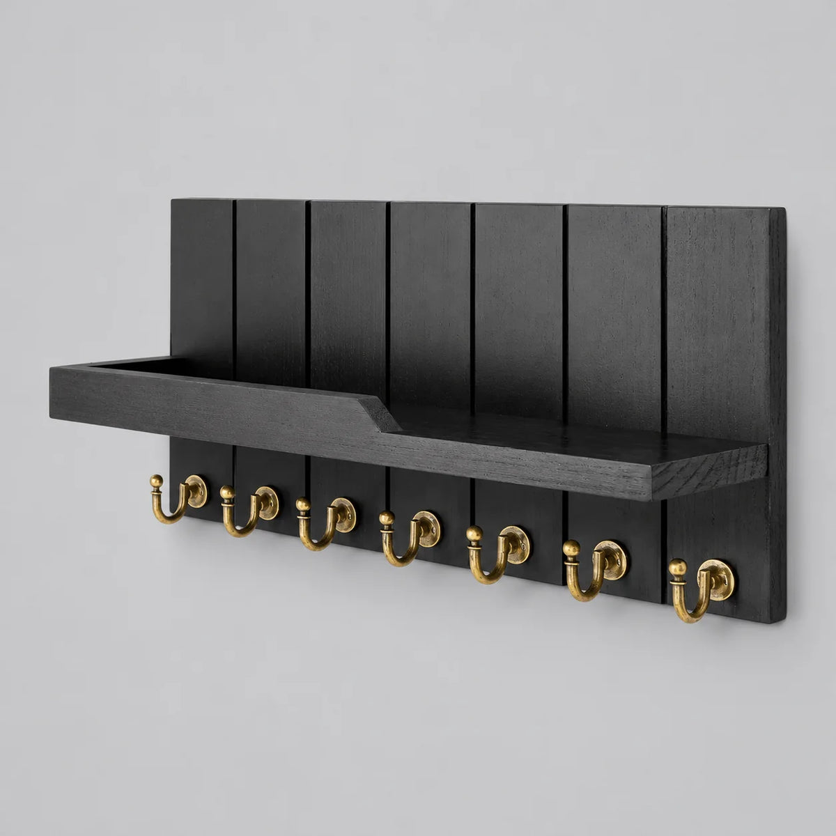 Porte-manteau mural noir avec tablette, panneau rainuré et sept crochets dorés, vue complète sur fond gris