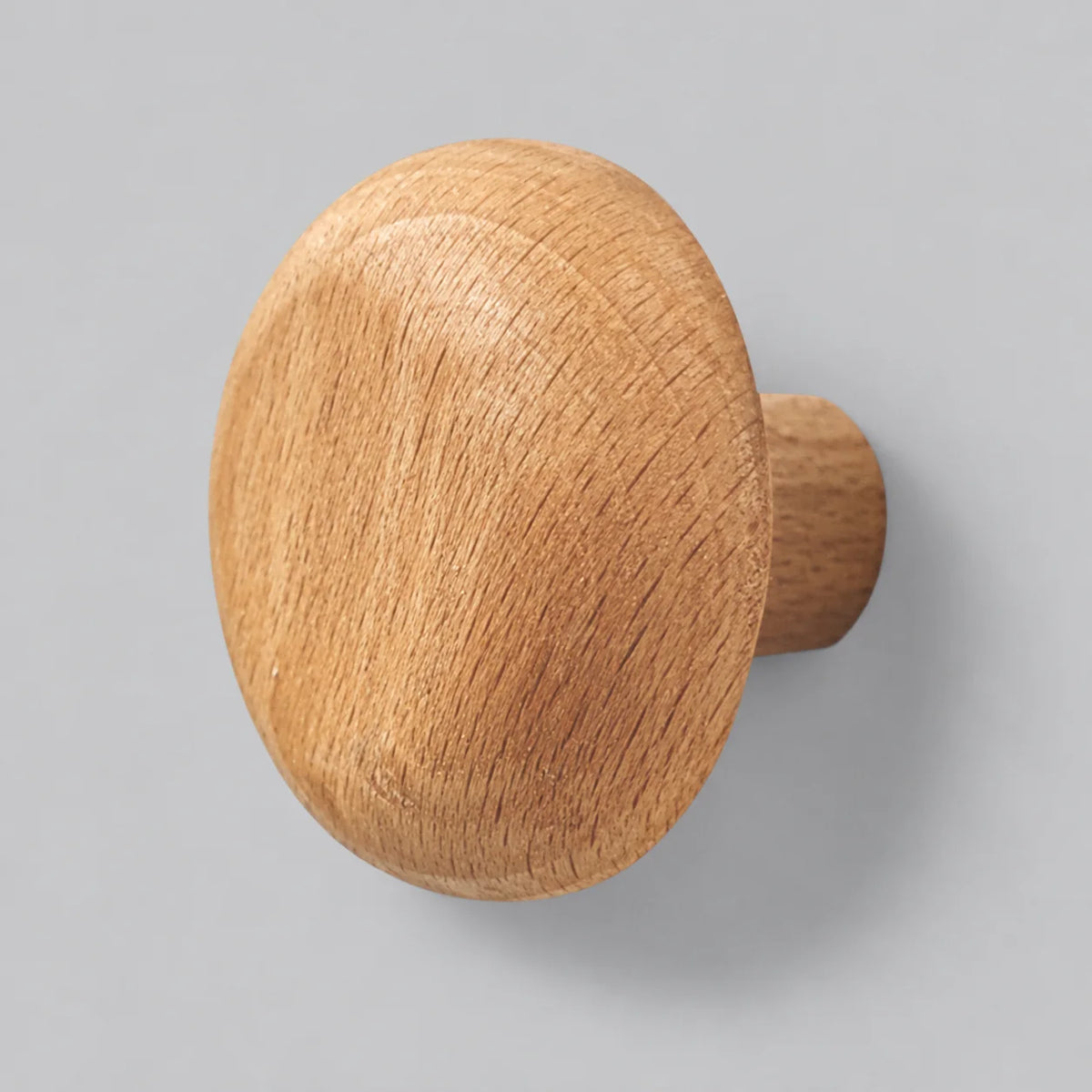 Patère murale ronde en bois naturel clair sur fond gris