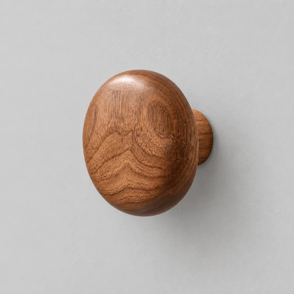 Patère ronde en bois brun foncé, vue oblique sur fond gris Image