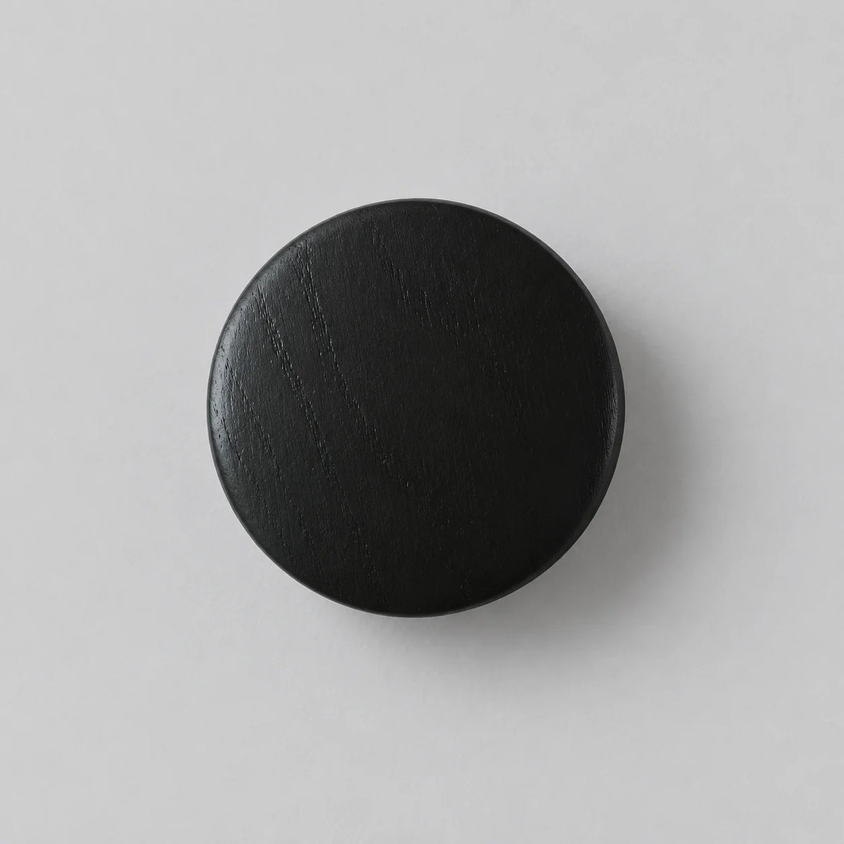 Patère murale ronde noire en bois sur fond gris