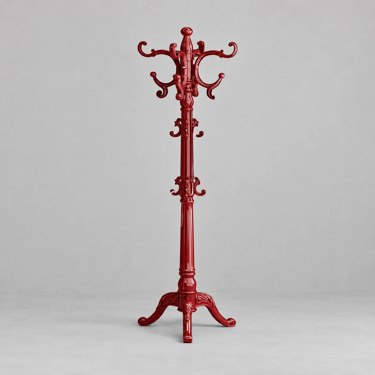 Porte-manteau perroquet rouge sculpté sur pied, vue entière sur fond gris