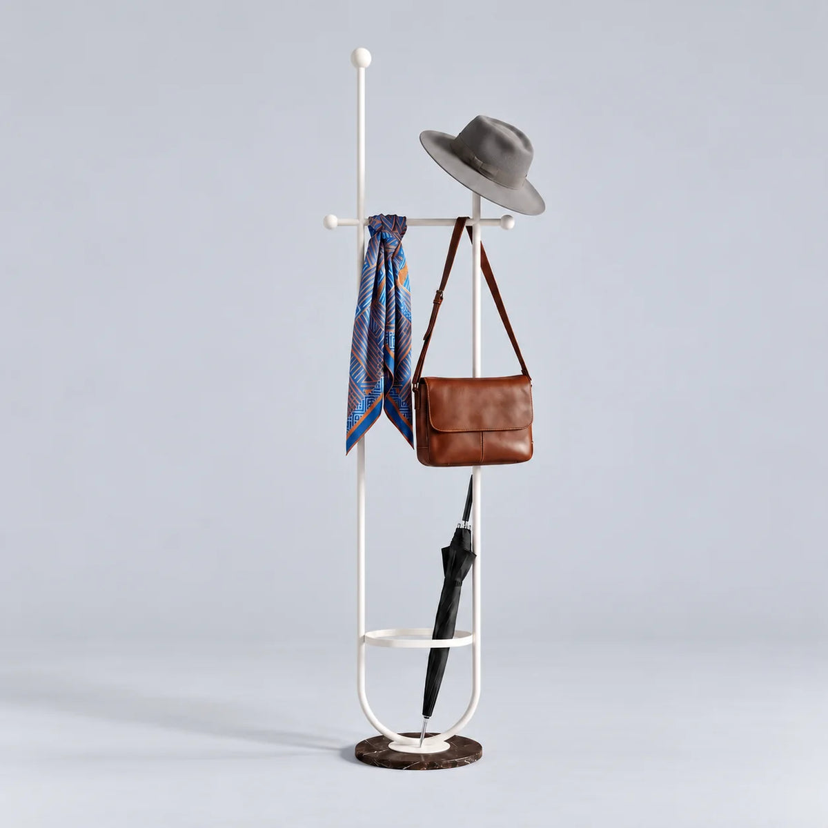 Porte-manteau sur pied en métal blanc à deux montants, traverse à boules, anneau porte-parapluie et base ronde en marbre sombre veiné, avec chapeau, foulard, sac et parapluie