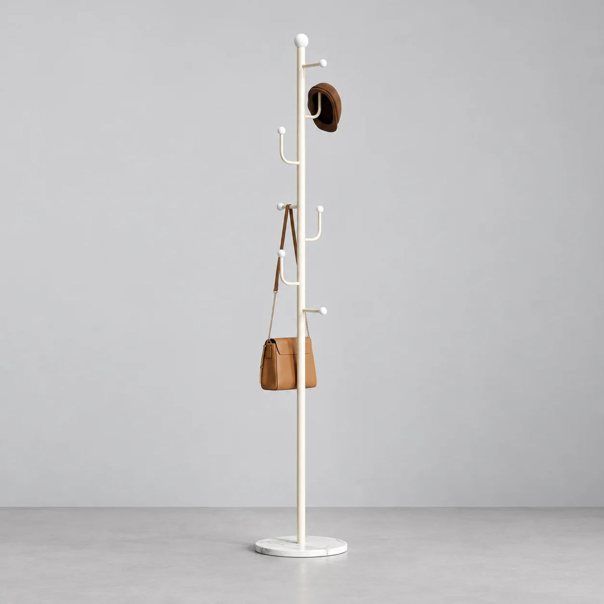 Porte-manteau sur pied blanc avec socle rond, chapeau et sac, sur fond gris Image