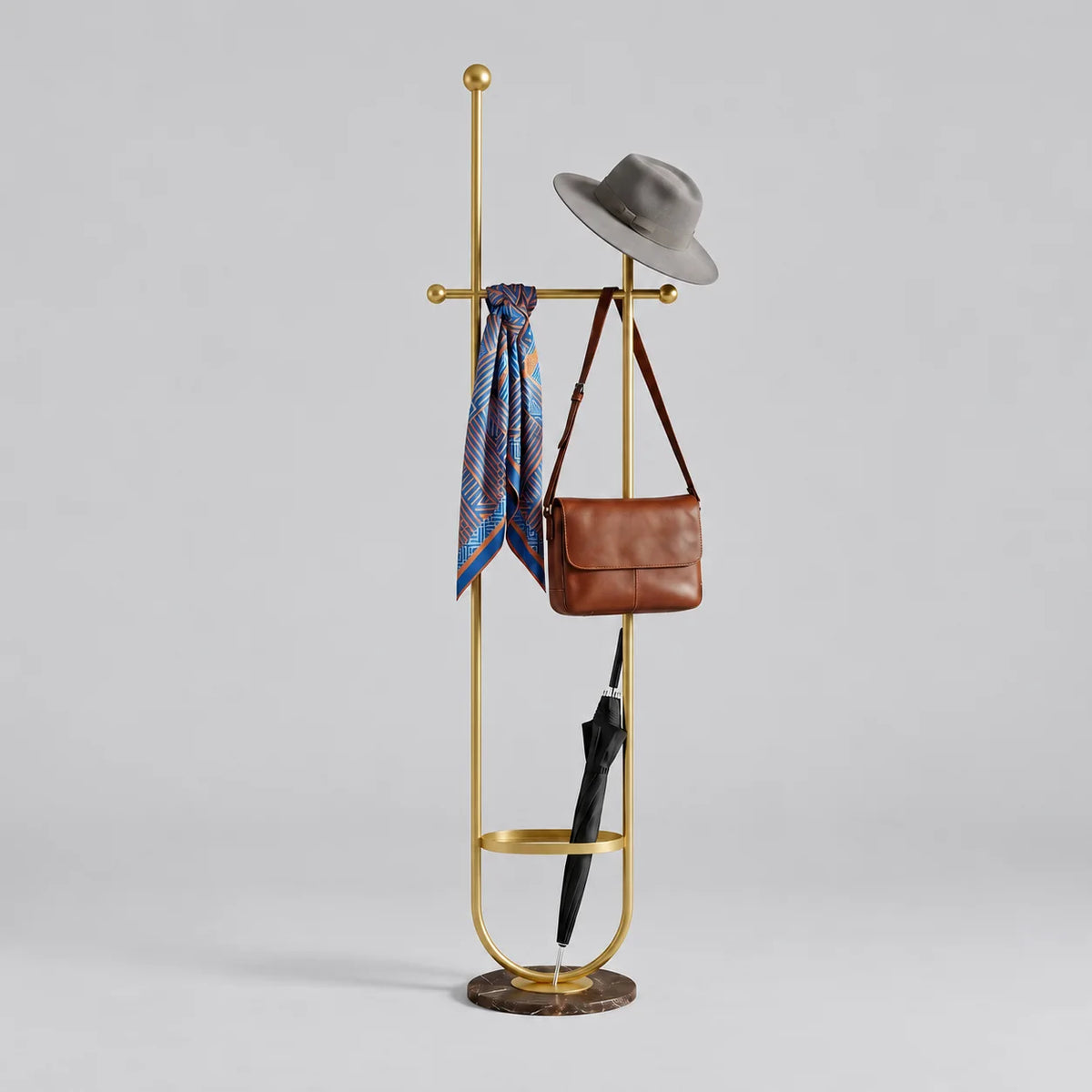 Porte-manteau sur pied en métal doré à deux montants, traverse à boules, anneau porte-parapluie et base ronde sombre, avec chapeau, foulard, sac et parapluie