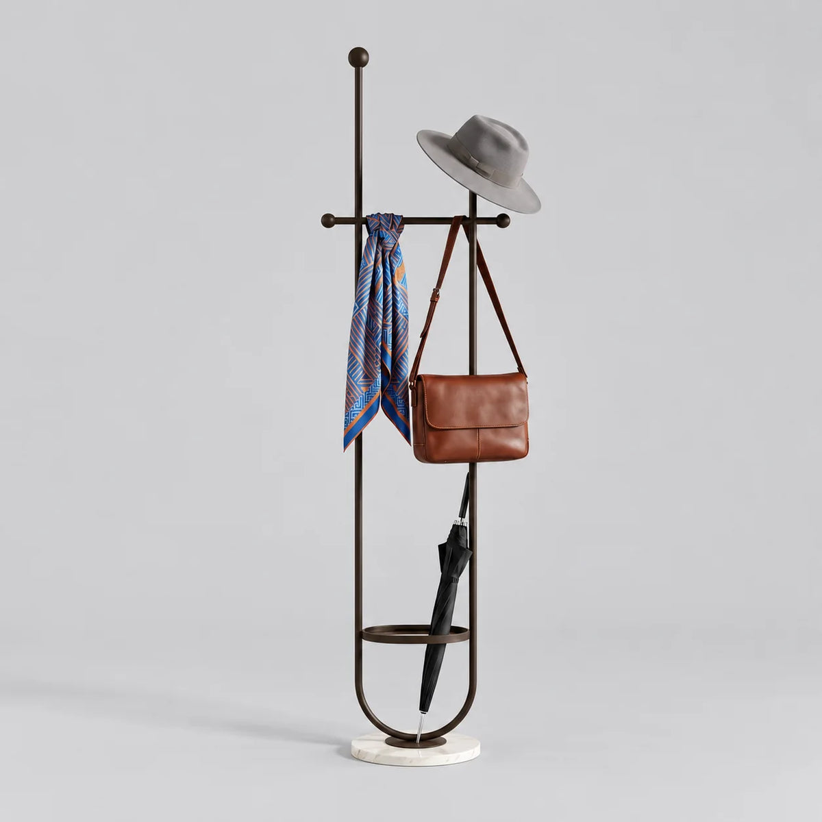 Porte-manteau sur pied en métal noir à deux montants, traverse à boules, anneau porte-parapluie et base ronde blanche veinée, avec chapeau, foulard, sac et parapluie