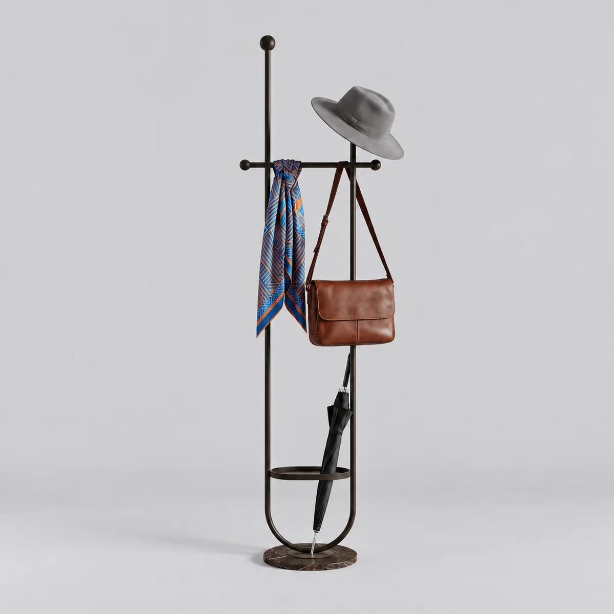 Porte-manteau sur pied en métal noir à deux montants, traverse à embouts ronds, anneau porte-parapluie et base ronde sombre, avec chapeau, foulard, sac et parapluie