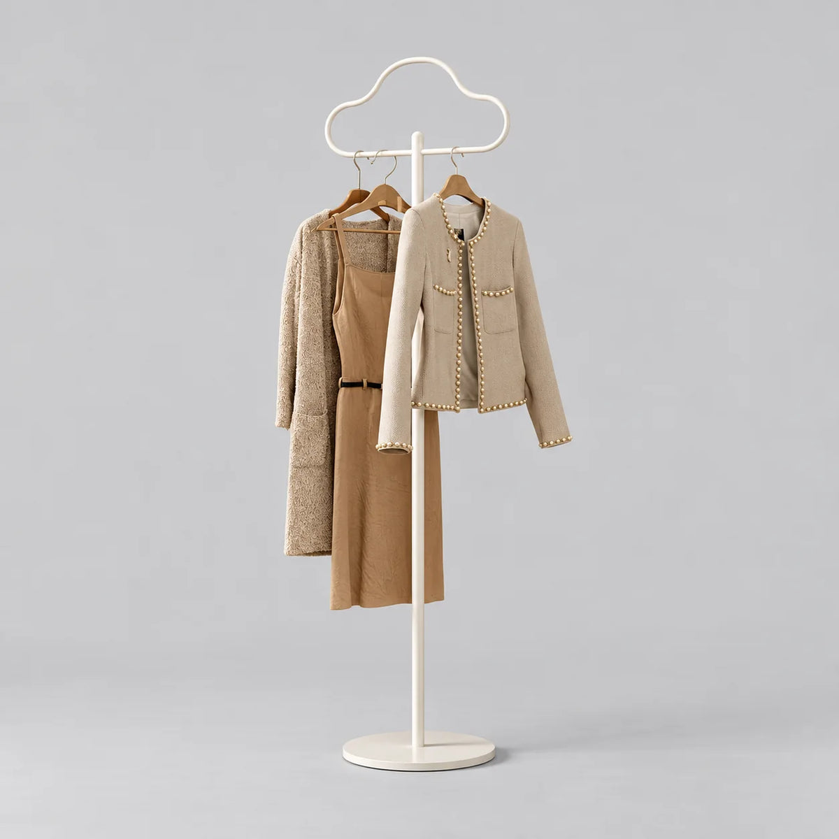 Porte-manteau sur pied Nuage blanc, portant trois vêtements sur fond gris neutre