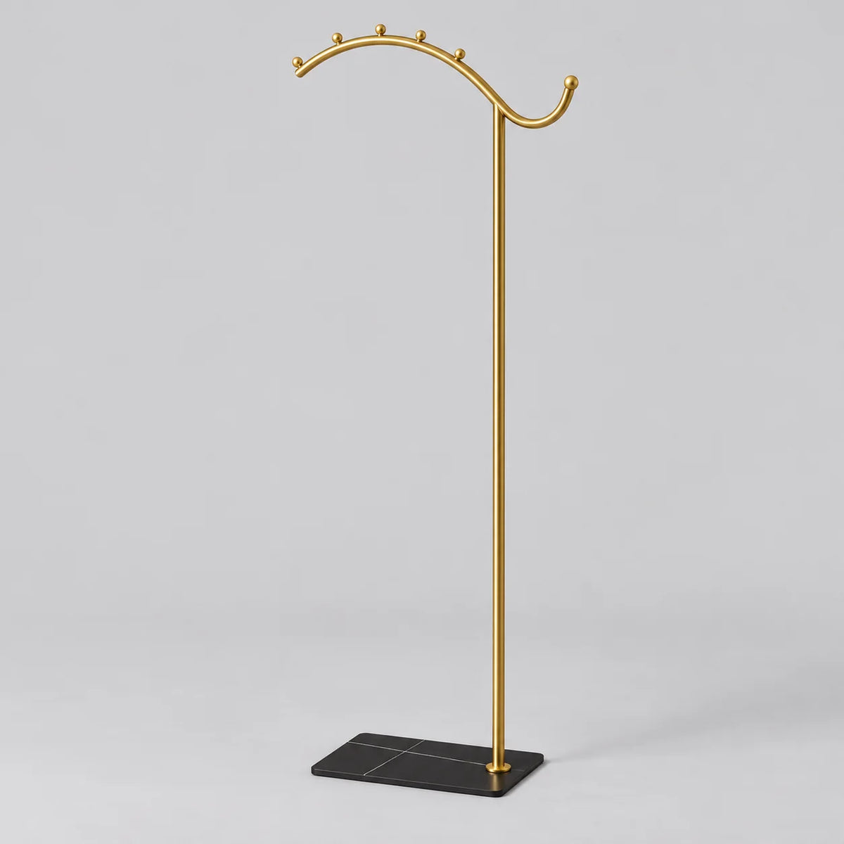 Porte-manteau sur pied voûte dorée, tige dorée et socle noir, vue complète sur fond gris