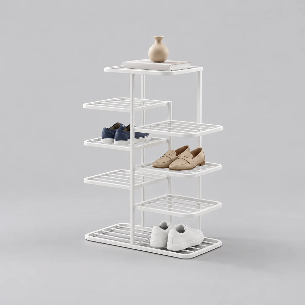 Range-chaussures blanc en fer forgé à étagères alternées, avec vase et trois paires de chaussures, sur fond gris