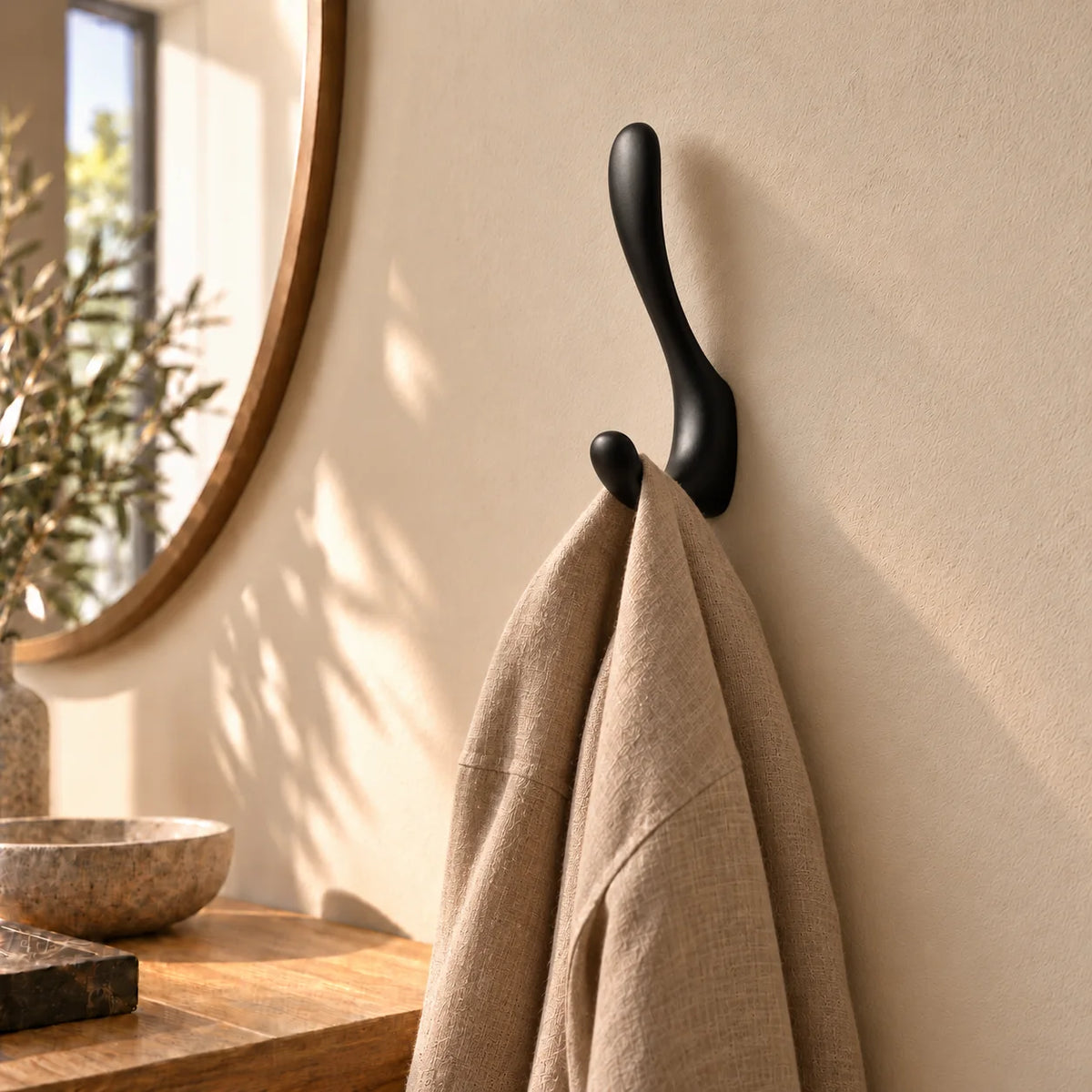 Patère crochet noir avec écharpe taupe suspendue dans une entrée