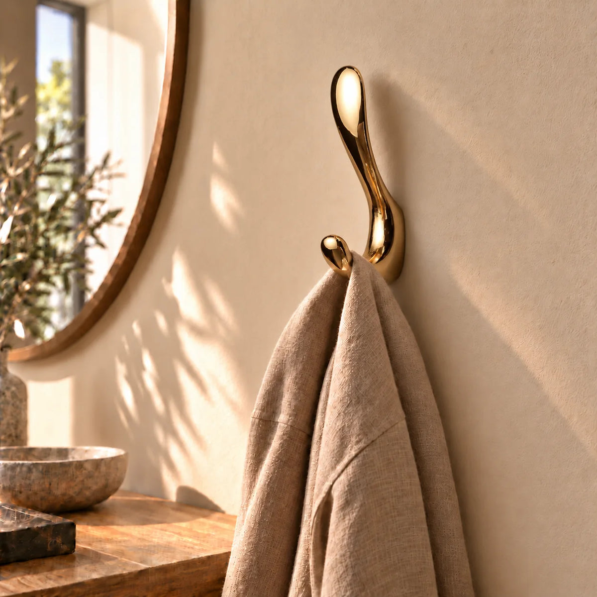 Patère crochet doré brillant avec écharpe taupe suspendue dans une entrée