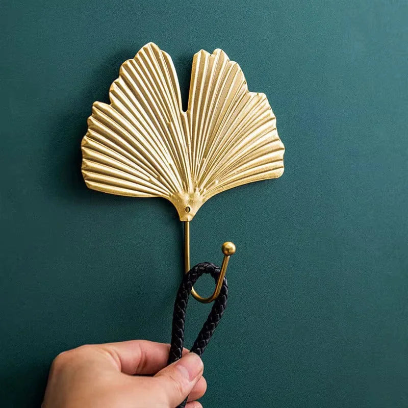 Patère Feuille dorée avec accessoire sur mur bleu-vert, photo originale