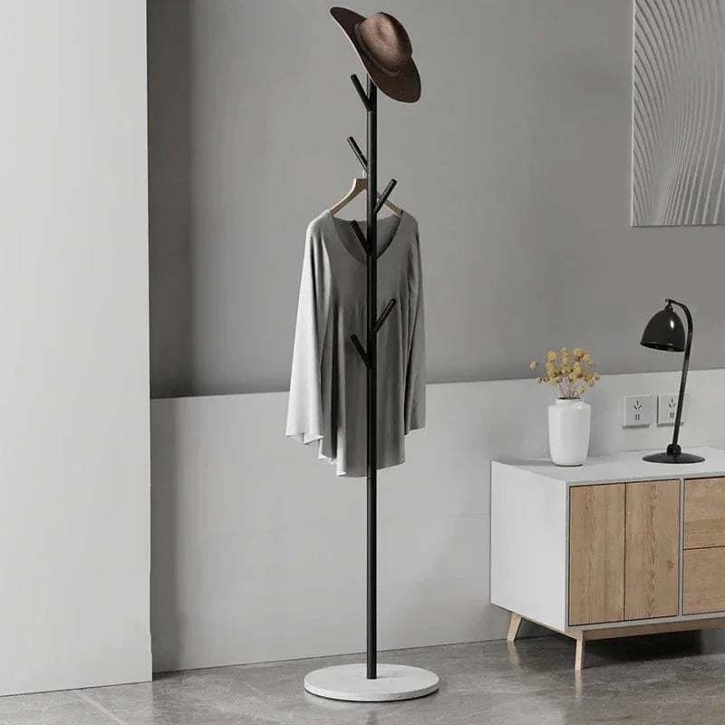 Porte-manteau arbre noir à base blanche avec manteau dans un intérieur gris, photo originale