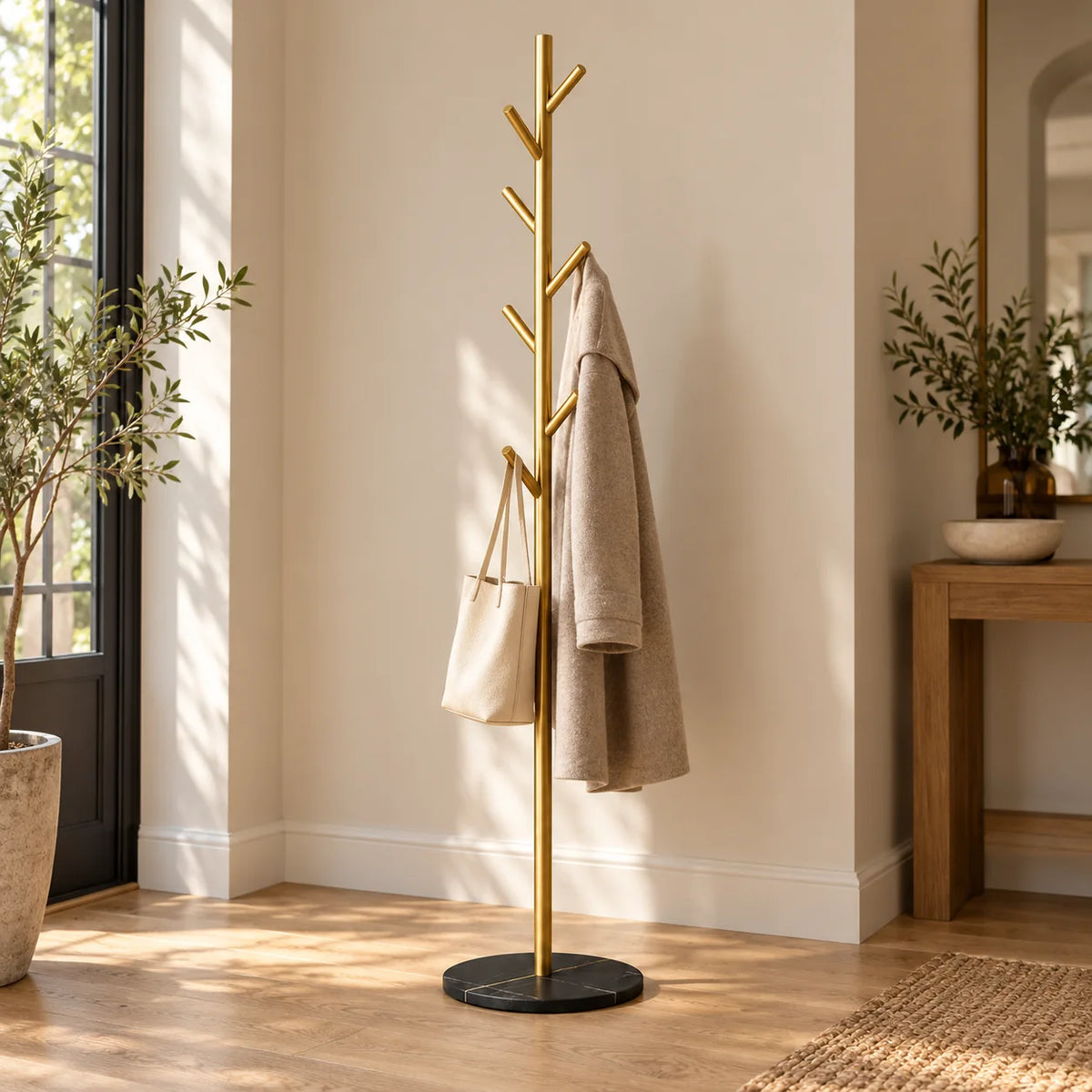 Porte-manteau arbre doré sur base noire marbrée avec manteau beige et sac dans une entrée Image