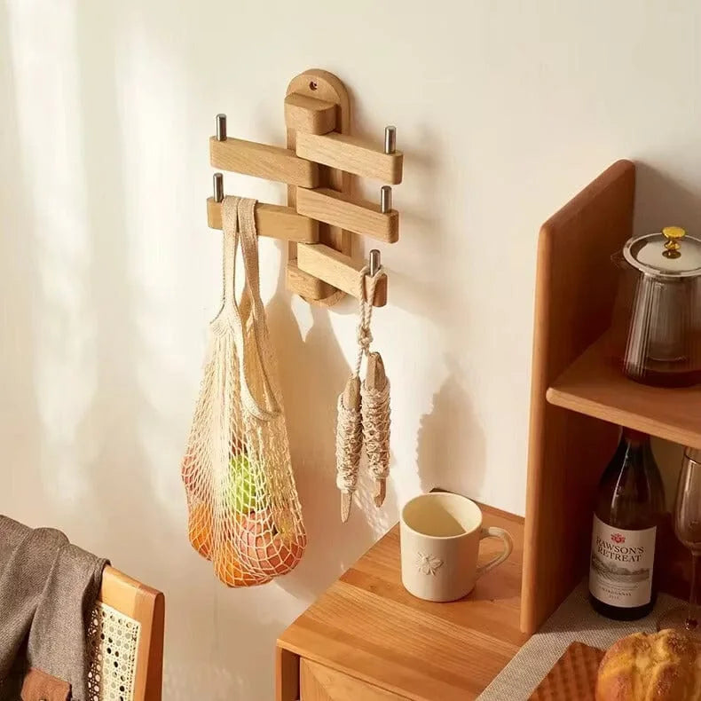 Porte-manteau mural pivotant en bois installé dans une pièce, avec deux sacs suspendus