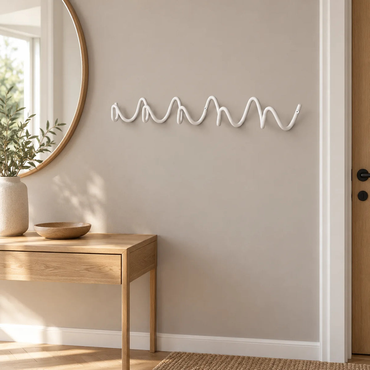 Porte-manteau mural ondulé blanc installé au-dessus d’une console dans une entrée