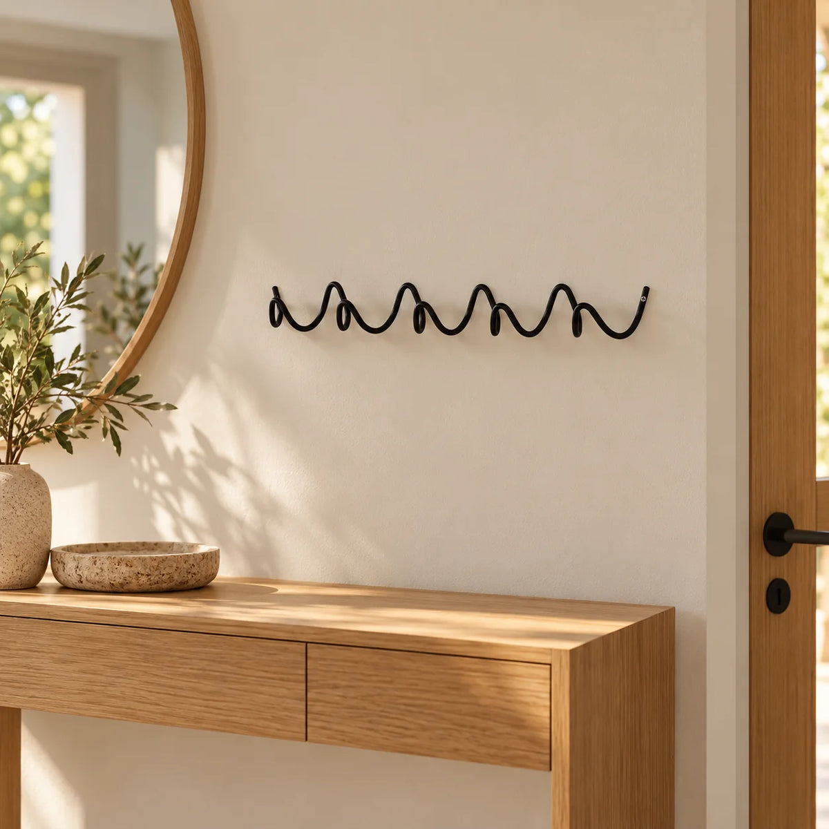 Porte-manteau mural Vrille noir de 54 cm installé au-dessus d’une console dans une entrée Image