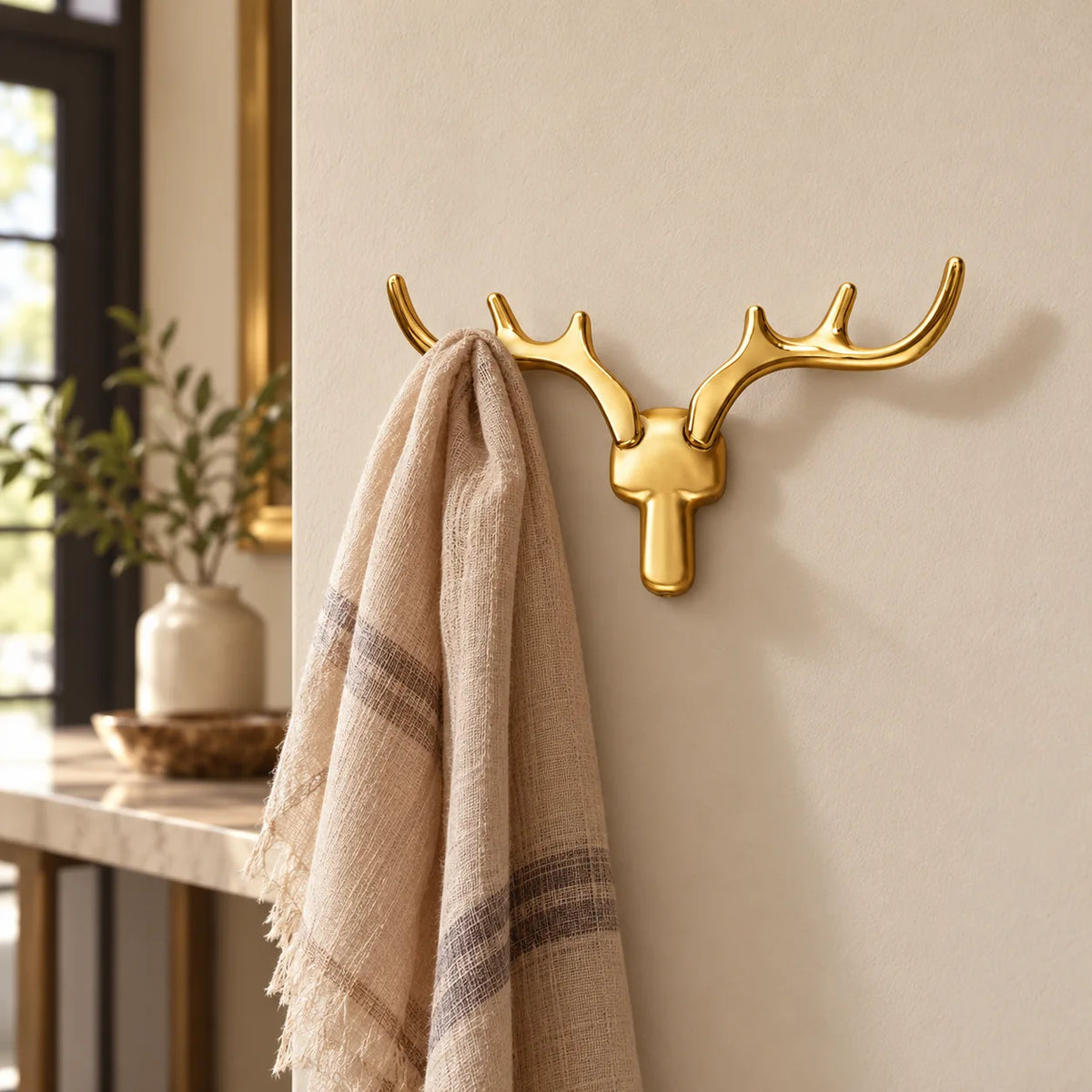 Patère cerf dorée portant une écharpe dans une entrée