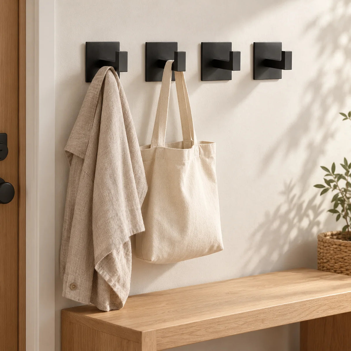 Quatre patères Original noires dans une entrée avec veste et sac