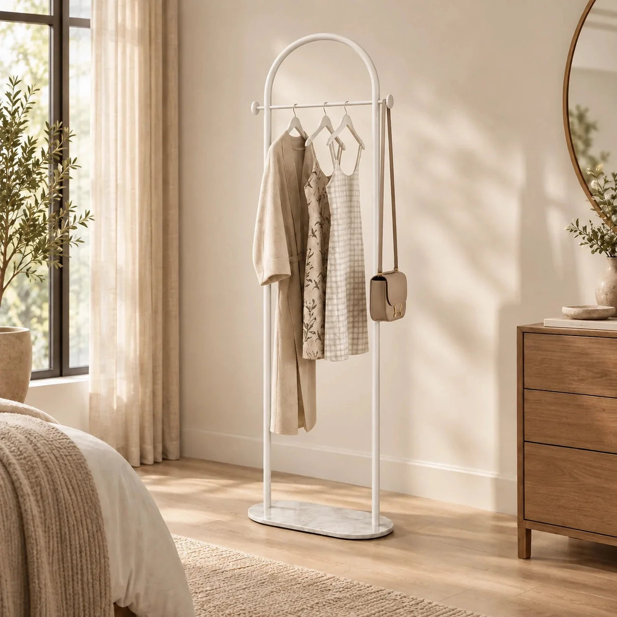 Porte-manteau courbé blanc dans une chambre lumineuse avec vêtements suspendus