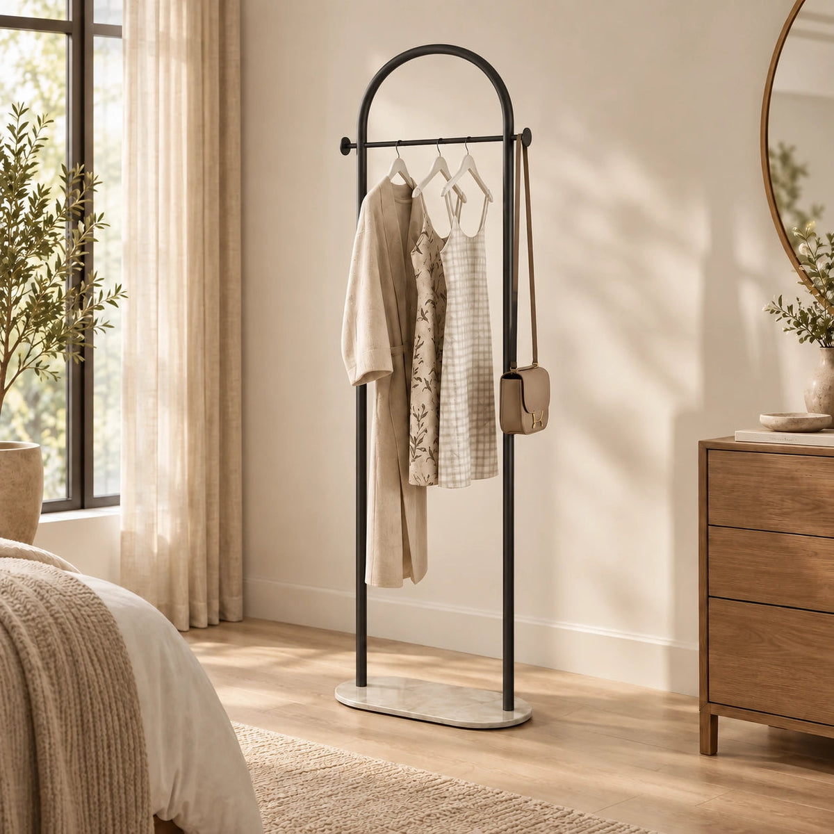 Porte Manteau sur Pied Courbé noir installé dans une chambre lumineuse, avec vêtements et sac suspendus