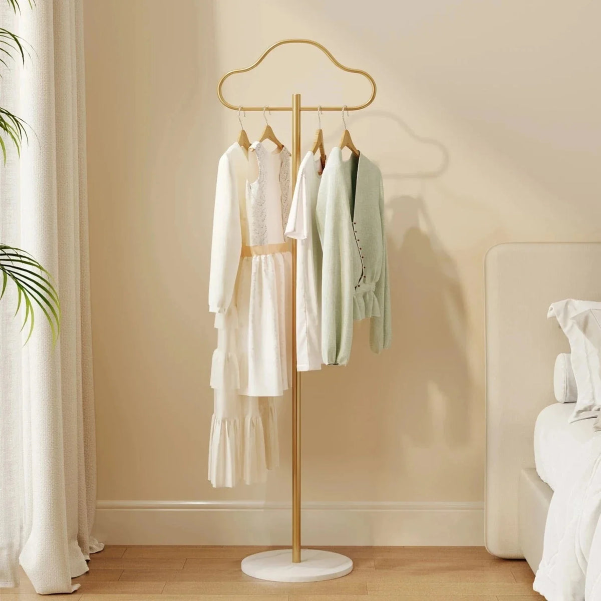 Porte-manteau sur pied doré en forme de nuage avec vêtements dans une chambre claire