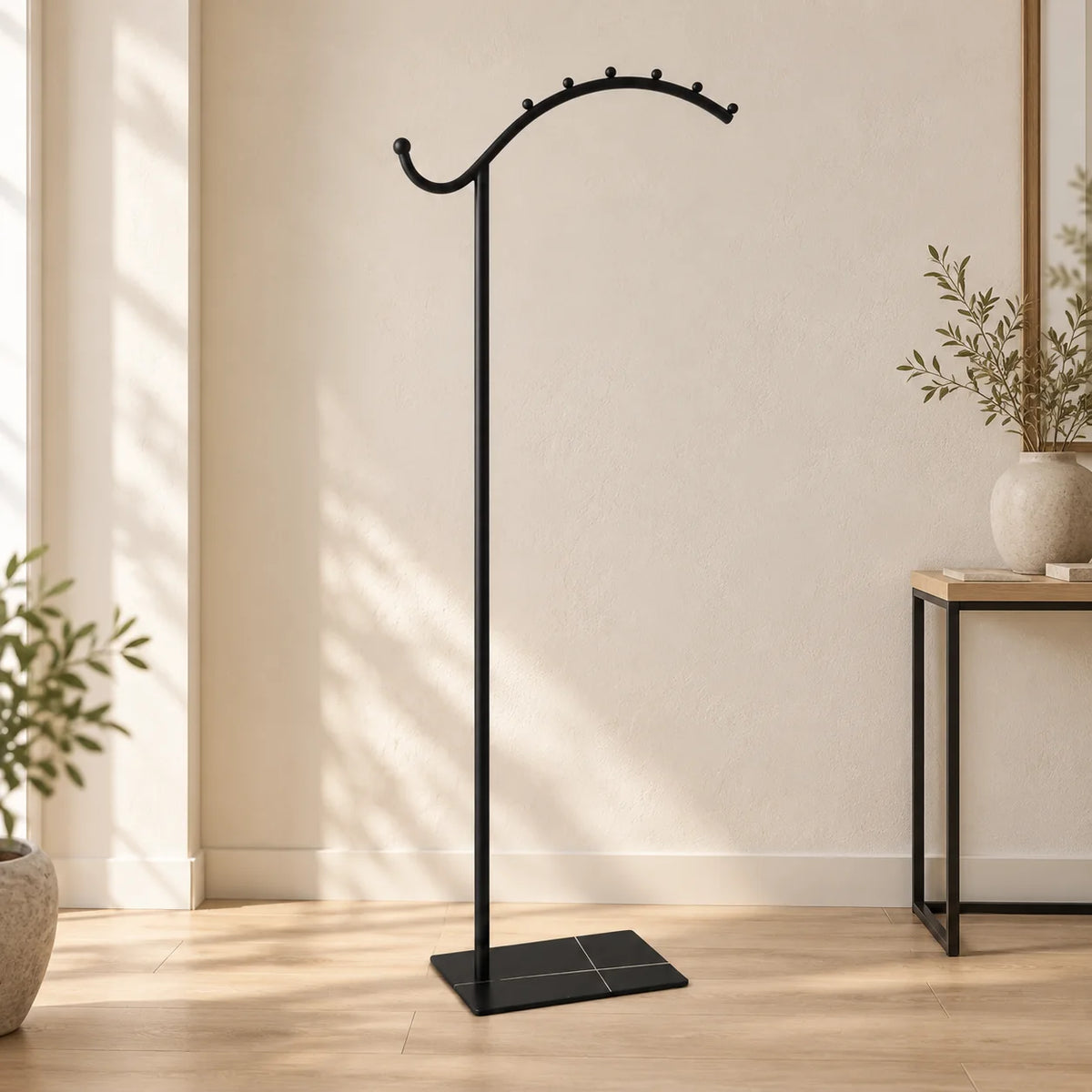Porte-manteau voûté noir avec socle noir dans une entrée lumineuse, entièrement visible