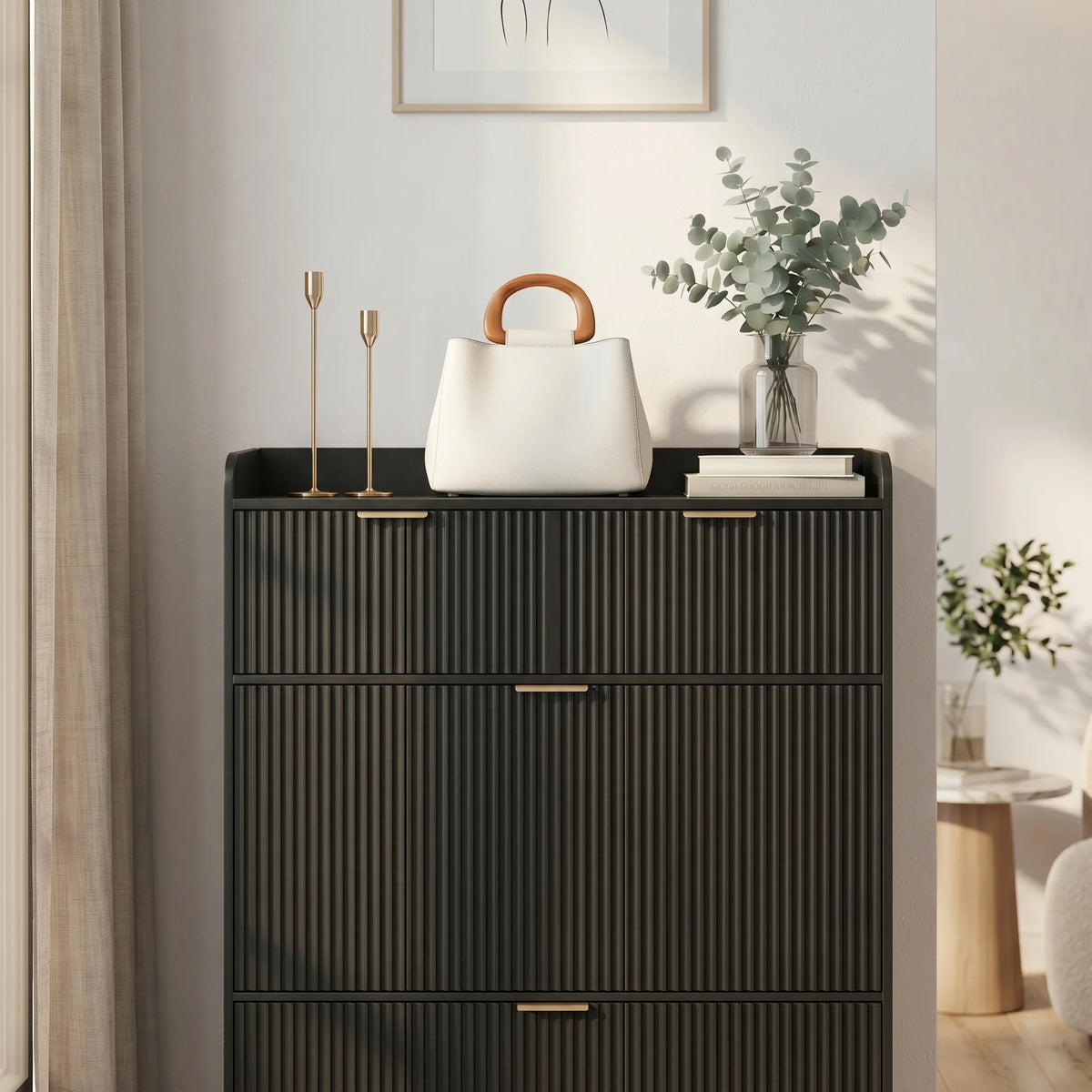 Vue rapprochée du meuble noir cannelé, des poignées dorées et de sa décoration