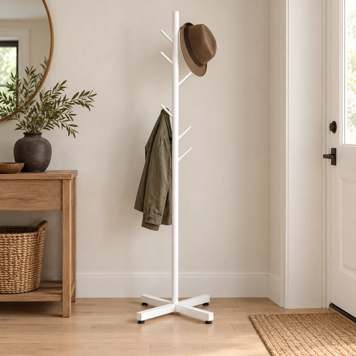 Porte-manteau arbre blanc à base croisée avec chapeau et veste dans une entrée lumineuse