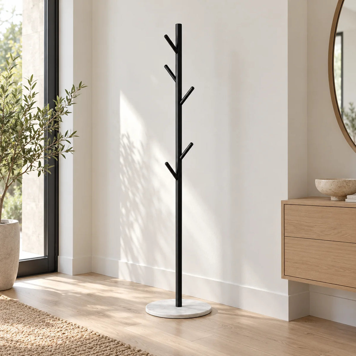 Porte-manteau arbre noir à cinq patères sur base blanche dans une entrée lumineuse