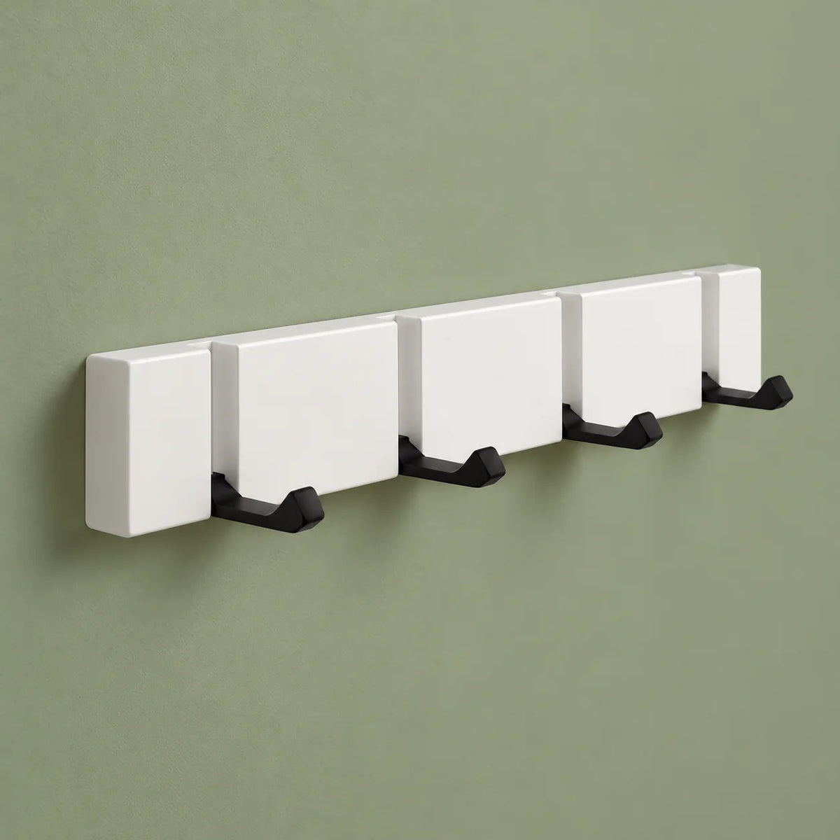 Vue de trois quarts du porte-manteau mural blanc à quatre crochets rabattables sur fond vert sauge