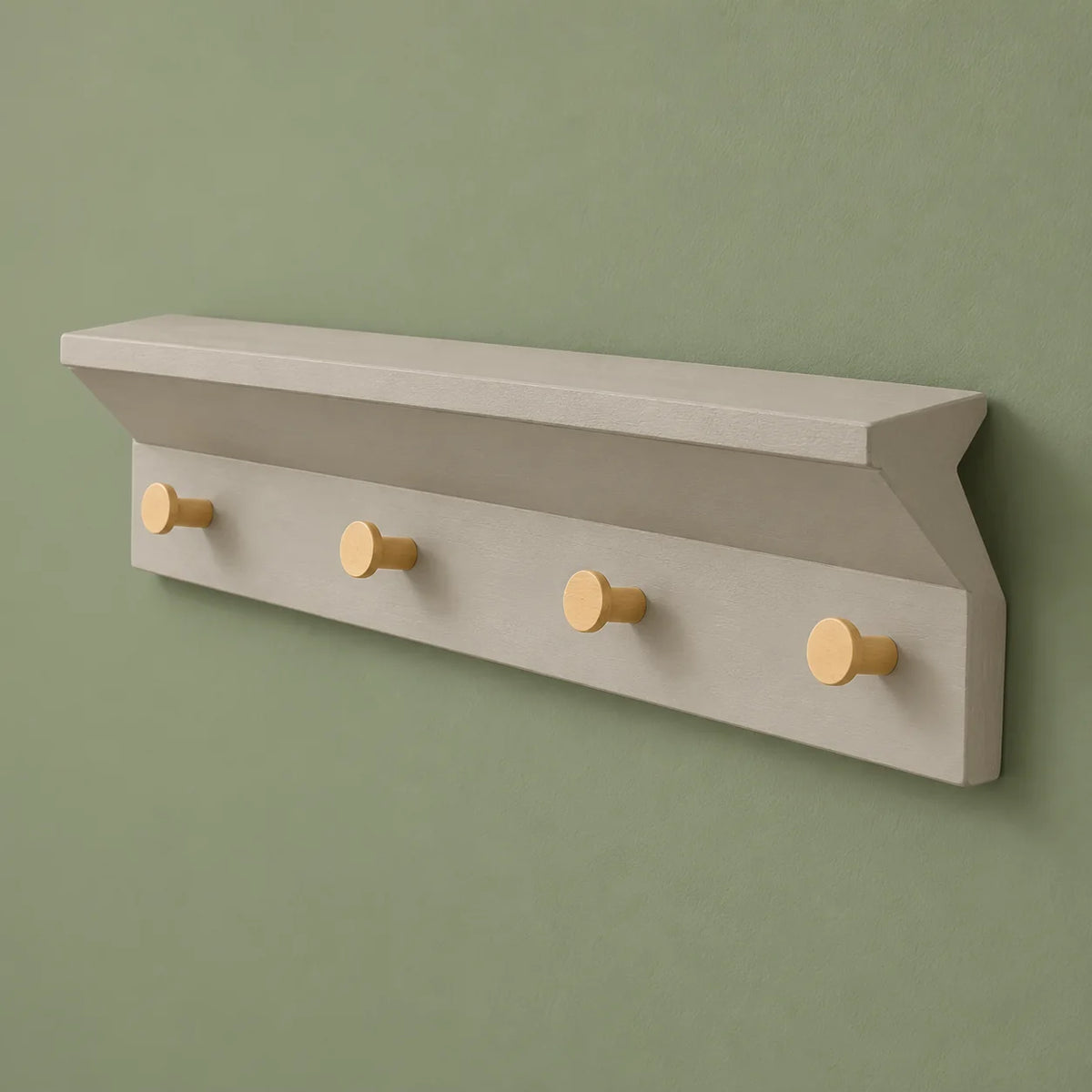 Vue de trois quarts du porte-manteau mural gris à tablette et quatre patères sur fond vert sauge