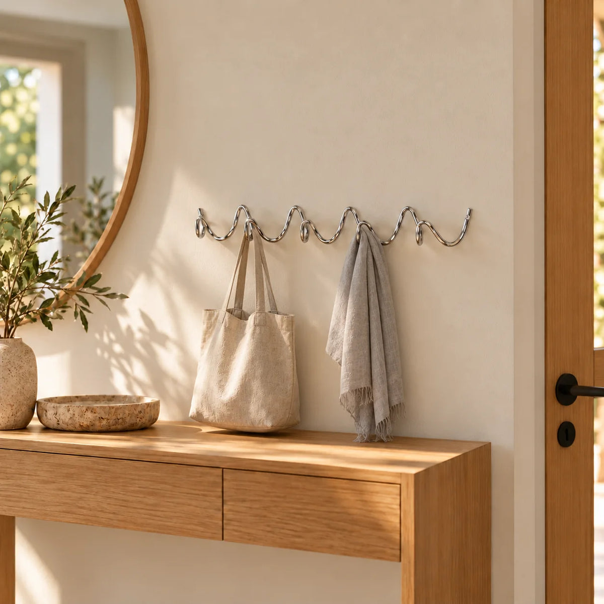 Porte-manteau mural Vrille chrome portant un sac en toile et une écharpe dans une entrée
