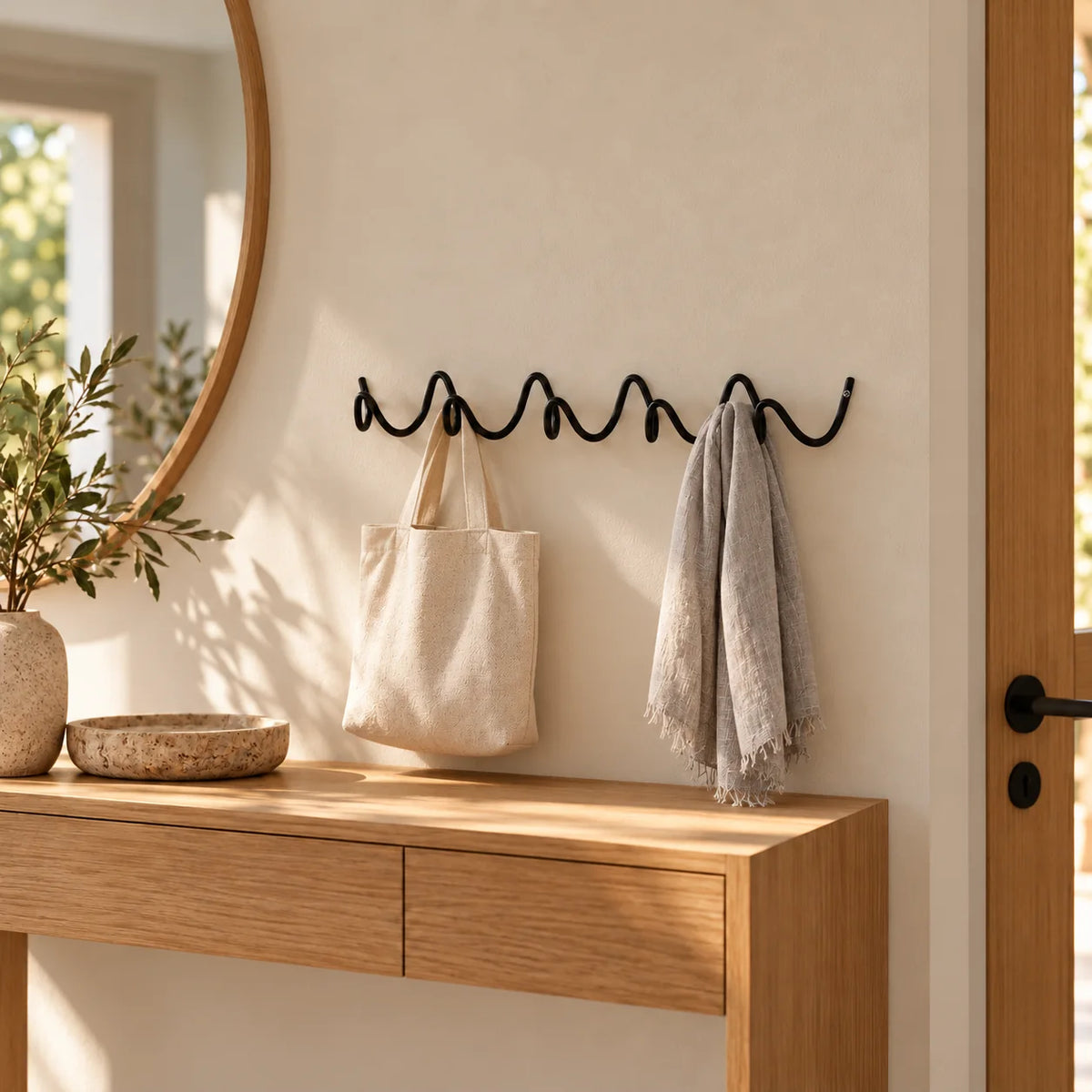 Porte-manteau mural Vrille noir portant un sac en toile et une écharpe dans une entrée