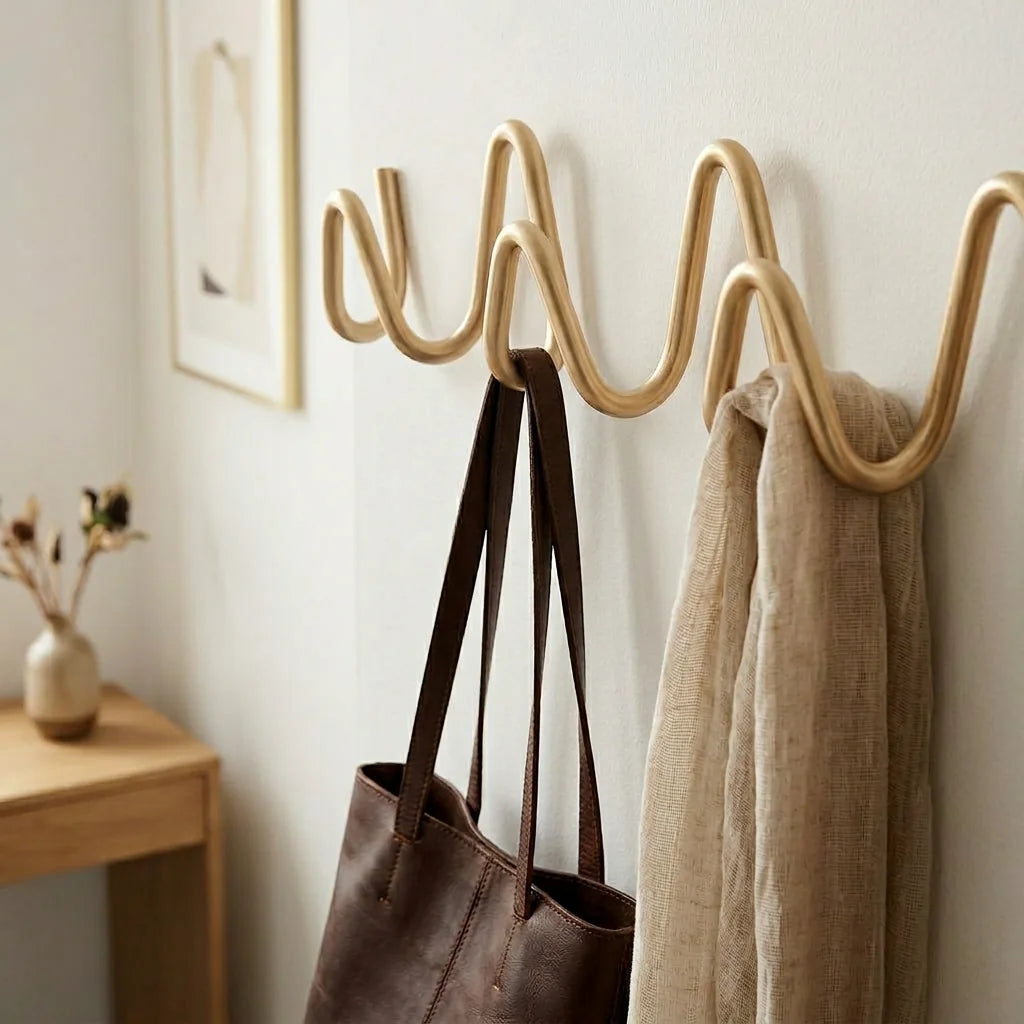 Gros plan du porte-manteau mural doré avec sac et vêtements suspendus