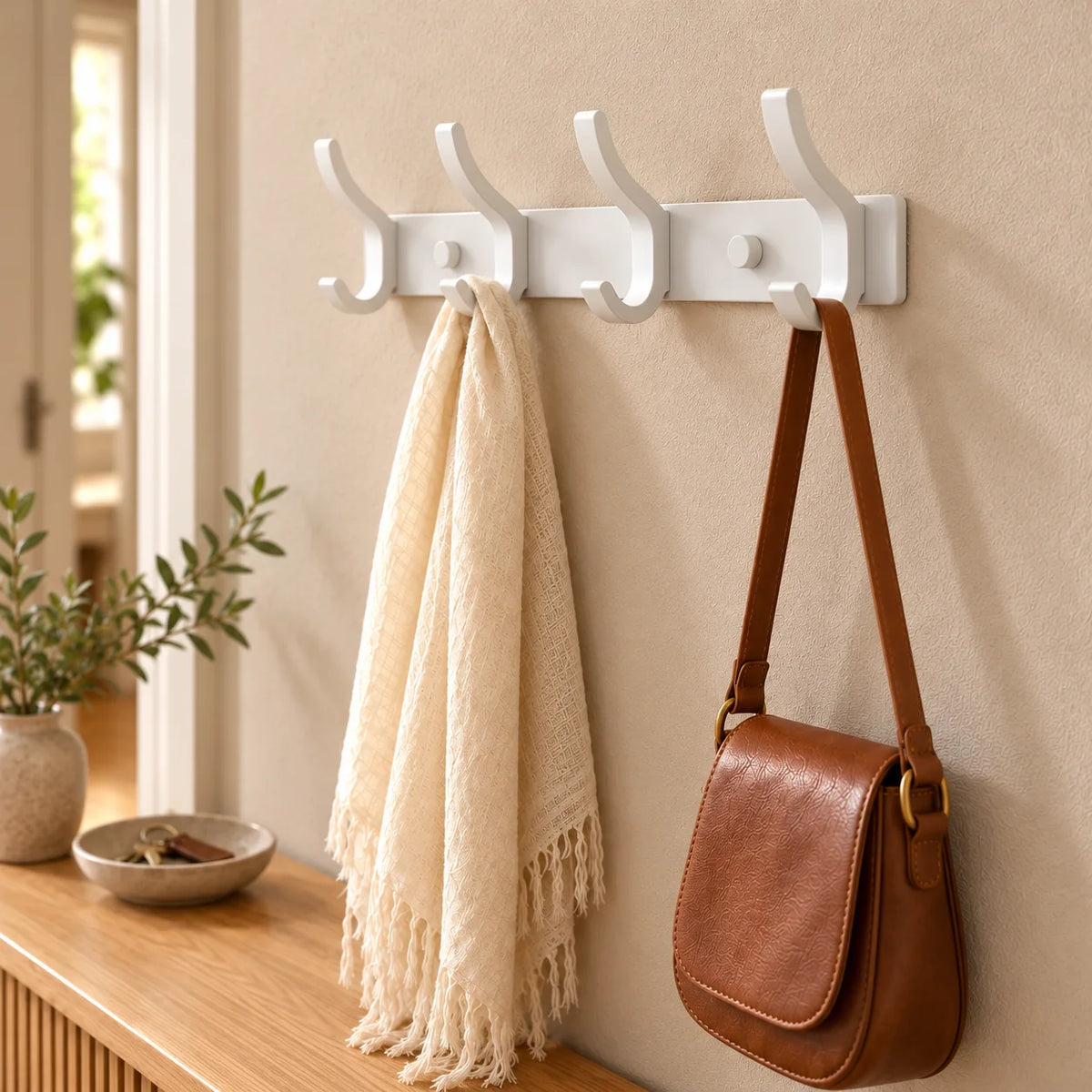 Vue rapprochée en biais du porte-manteau blanc à quatre crochets dans la même entrée