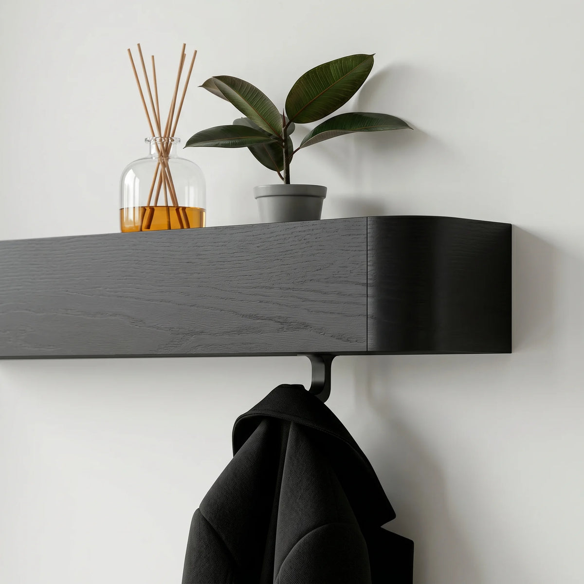 Vue oblique du porte-manteau mural en bois noir avec patère, manteau, diffuseur et plante