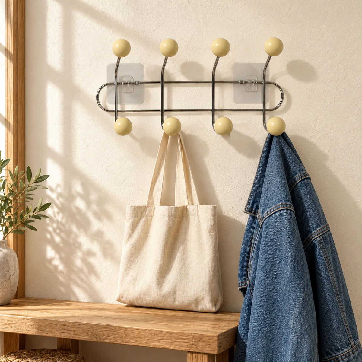 Porte-manteau mural chromé à quatre bras avec sac et veste dans une entrée ensoleillée