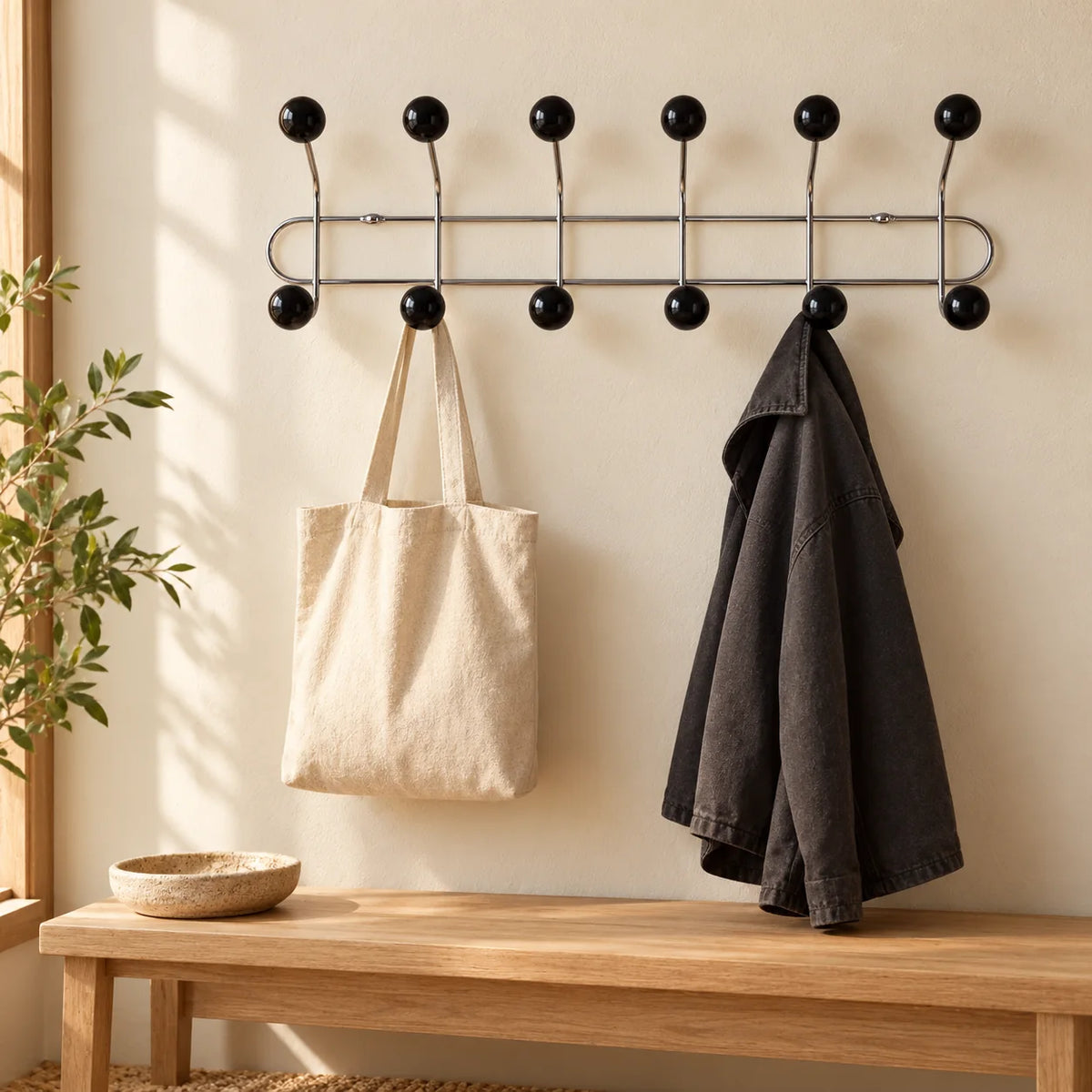 Porte-manteau mural chromé à six bras noirs avec sac et veste dans une entrée