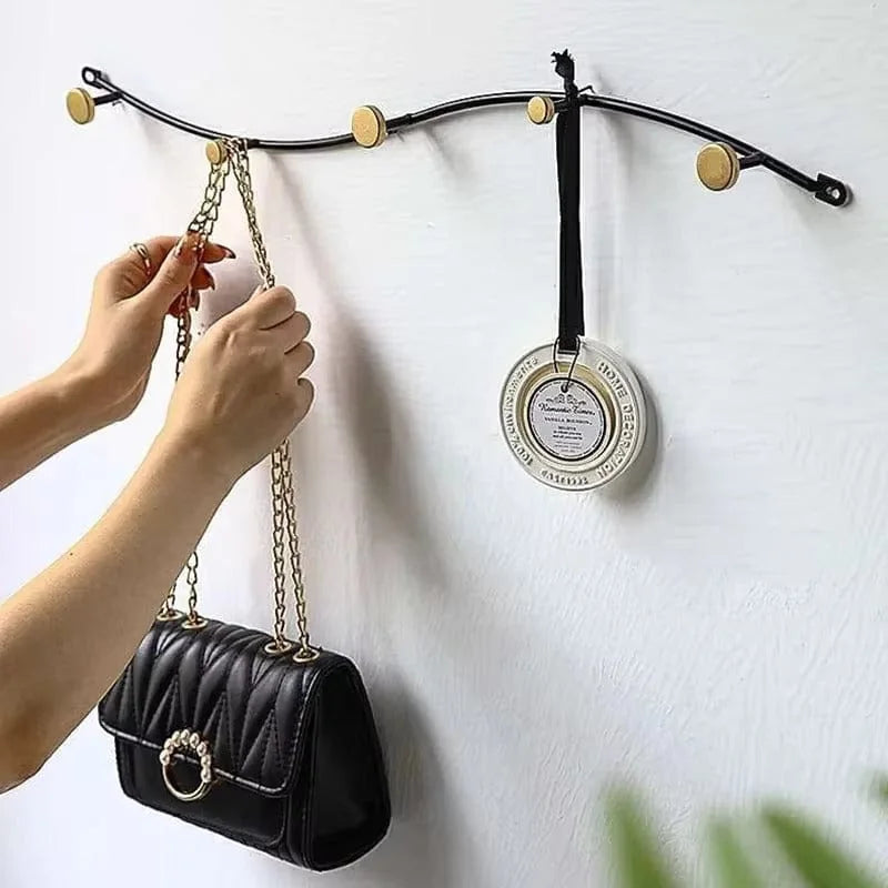 Photo d'origine du porte-manteau mural vague noir avec cinq patères dorées, un sac et un accessoire suspendus