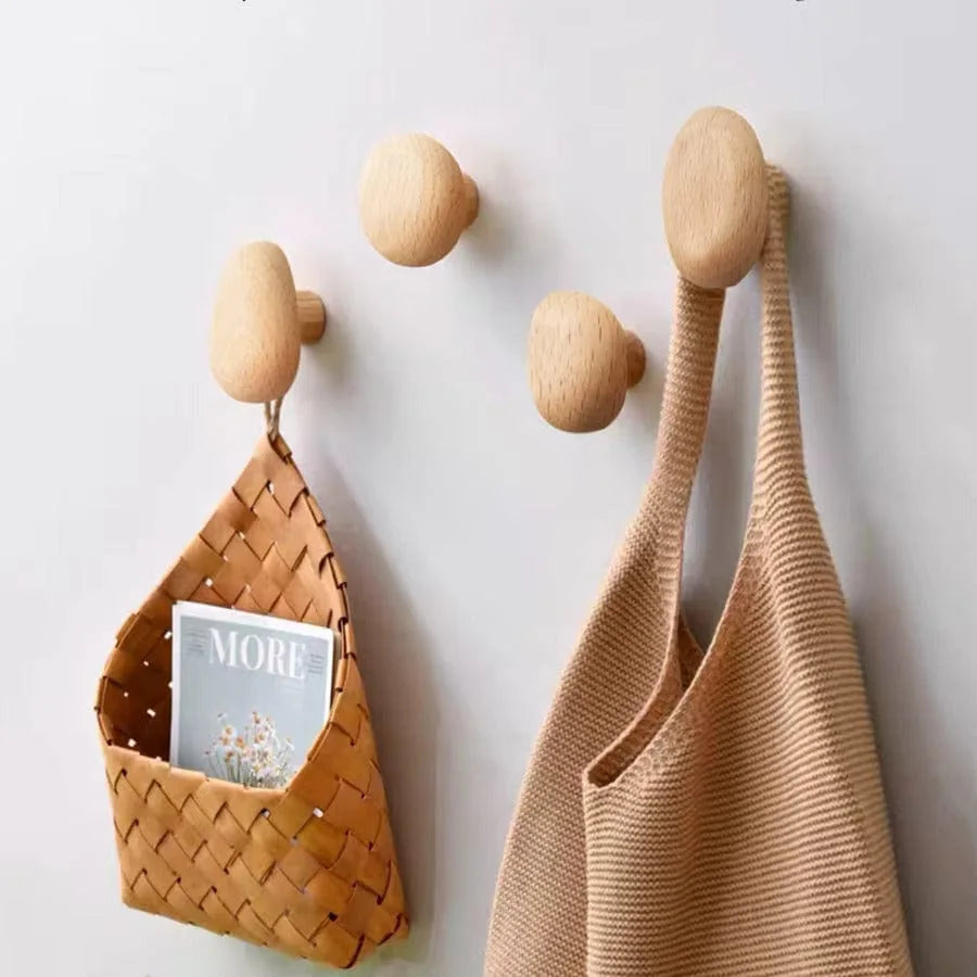 Patères ovales en bois naturel avec panier et sac sur mur clair