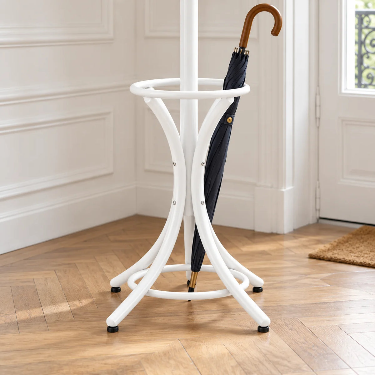 Détail de l’anneau porte-parapluies et des pieds courbés du porte-manteau blanc